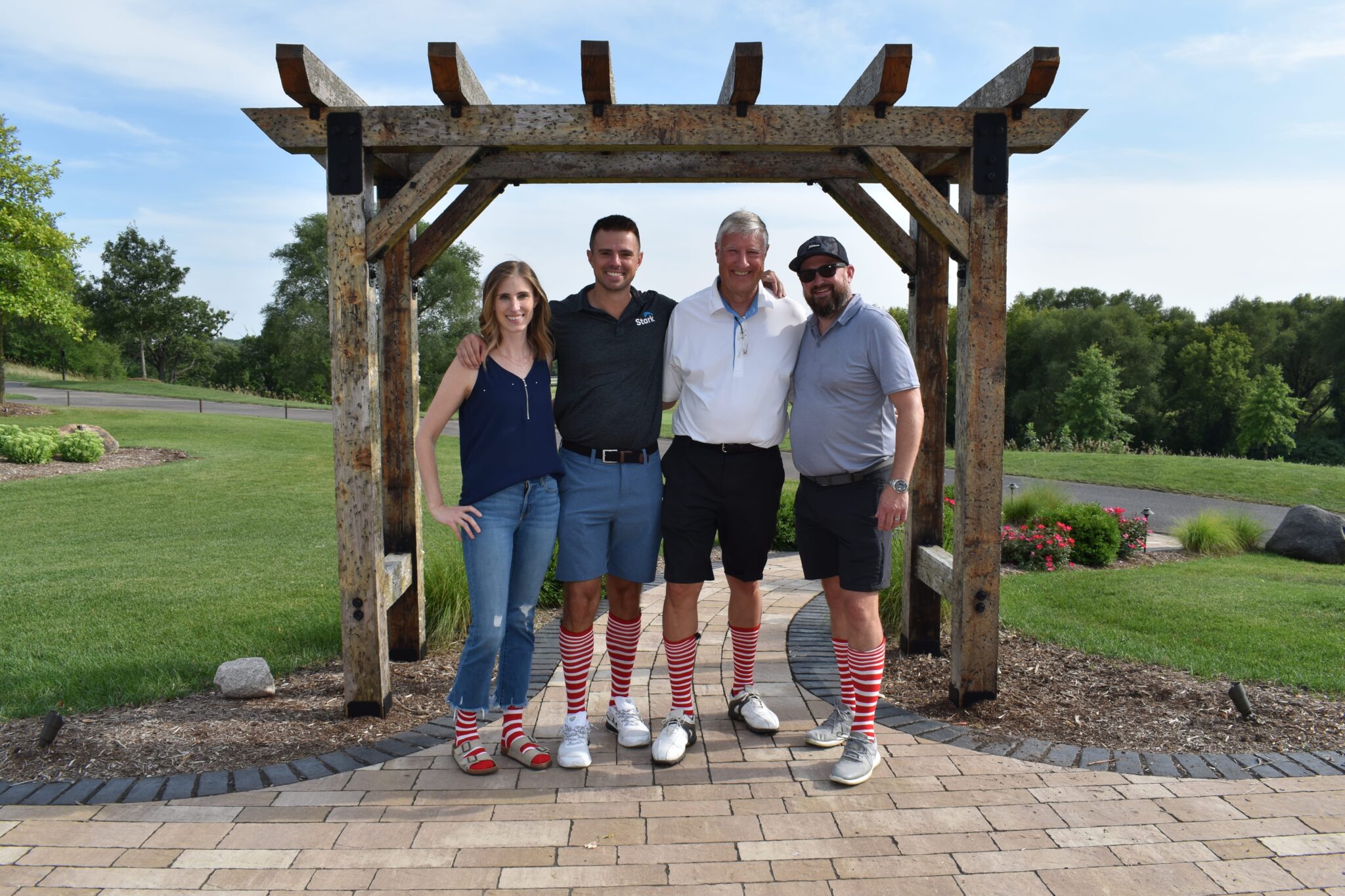DSC_0277 Four adults wearing striped socks in front of an arbor